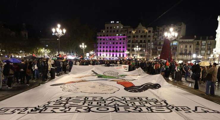 שלט עם דמותו של בנימין נתניהו והכיתוב: "ישראל מדינת טרור" (צילום: REUTERS/Pankra Nieto) מפגינים ב בילבאו ספרד לקראת משחק נבחרת פלסטין