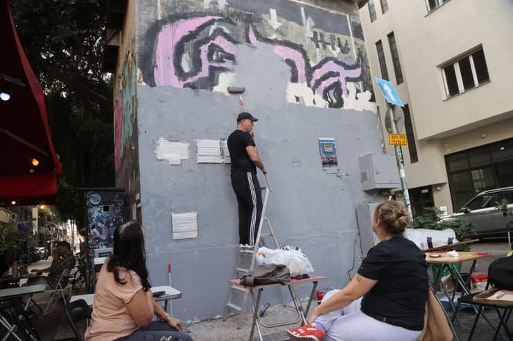 צוות של מתנדבים החל בתהליך ניקוי הקיר לקראת שחזור הציור. "המון משמעות עבור הדור הבא" (צילום: מוטי קמחי) צוות של מתנדבים החל בתהליך שחזור הציור של רצח רבין בשכונת פלורנטין בתל אביב