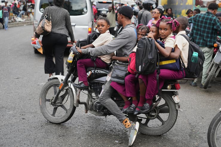 המשבר ההומניטרי הוא מהחמורים בעולם (צילום: AP Photo/Odelyn Joseph) רוכב אופנוע לוקח תלמידי בית ספר