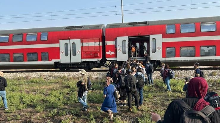 נוסעים עוזבים את קרון הרכבת שעצרה  באמצע הדרך