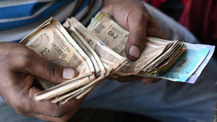 רוכל במומבאיי סופר שטרות של רופי (צילום: AFP/Indranil Mukherjee) רוכל במומבאיי סופר שטרות של רופי