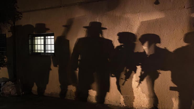 צלליות של חרדים וחיילים בכפר הפלסטיני כיפל חארס. אחת לכמה חודשים מתקיימת בכפר הילולה, שבמהלכה אלפי מתפללים פוקדים מבנה שמזוהה על פי המסורת כקבר יהושע בן נון. בזמן ההילולה מוטל עוצר על הכפר. התושבים נאלצים להסתגר בבתיהם, והמתפללים מסתובבים במקום, מאובטחים במאות חיילים ושוטרי מג"ב. כיפל חארס, הגדה המערבית, 24 באפריל 2025 (צילום: איתי רון, הארץ) איתי רון / הארץ צלליות של חרדים וחיילים בכפר הפלסטיני כיפל חארס. אחת לכמה חודשים מתקיימת בכפר הילולה, שבמהלכה אלפי מתפללים פוקדים מבנה שמזוהה על פי המסורת כקבר יהושע בן נון. בזמן ההילולה מוטל עוצר על הכפר. התושבים נאלצים להסתגר בבתיהם, והמתפללים מסתובבים במקום, מאובטחים במאות חיילים ושוטרי מג"ב. כיפל חארס, הגדה המערבית, 24 באפריל 2025