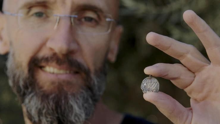 ד"ר פיליפ ווקוסבוביץ מרשות העתיקות עם תליון המנורה (צילום: אמיל אלג'ם, רשות העתיקות) ד"ר פיליפ ווקוסבוביץ מרשות העתיקות עם תליון המנורה