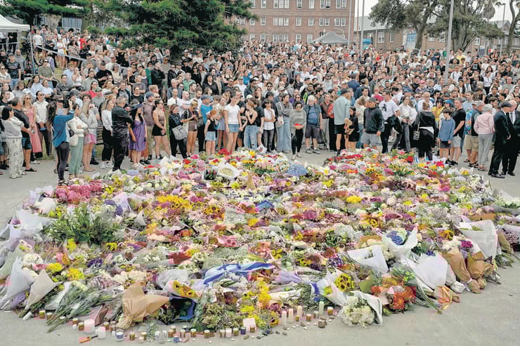 זרי פרחים ודגלי ישראל בזירת הפיגוע בבונדיי ביץ' (צילום: Saeed Khan/AFP) אתר הפיגוע בסידני