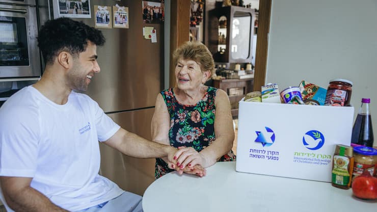 מתנדב מ"הקרן לרווחת נפגעי השואה" בביקור בביתה של ניצולת שואה   
