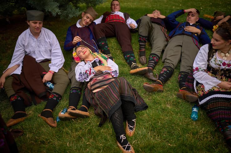 חברי להקה מסורתית מסרביה נחים בצל לקראת מצעד של הרכבים בינלאומיים ושל קבוצות אתניות מרומניה, המציגים תלבושות מסורתיות, ריקודים ושירים, בבוקרשט, רומניה, 21 ביוני 2025