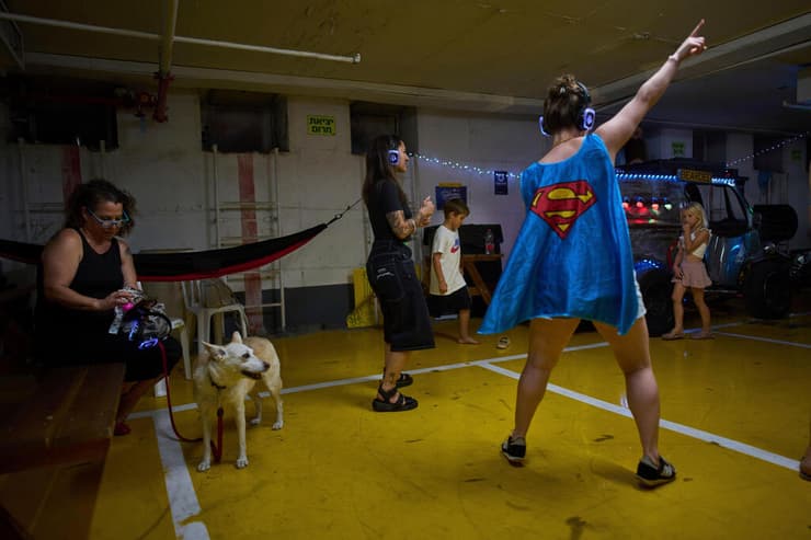 אנשים רוקדים במסיבת אוזניות בחניון תת-קרקעי המשמש מקלט מפני מתקפות טילים אפשריות מאיראן, בתל אביב, ישראל, 23 ביוני 2025