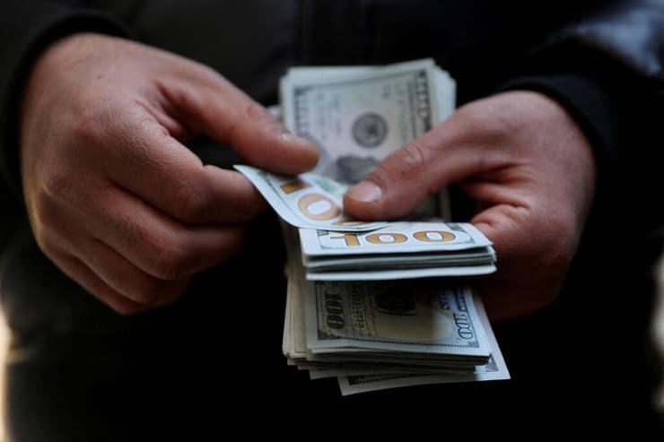 הריאל האיראני קורס. ב-2015 דולר אחד היה שווה 32 אלף ריאל, היום - 1.38 מיליון (צילום: Majid Asgaripour/WANA (West Asia News Agency) via REUTERS ) טהרן איראן איש מחזיק שטרות של דולרים
