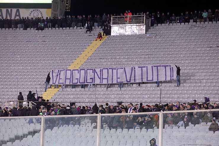 אוהדי פיורנטינה מניפים שלט עם הכיתוב "תתביישו" במשחק מול אודינזה (צילום: Gabriele Maltinti/Getty Images) אוהדי פיורנטינה מניפים שלט עם הכיתוב "תתביישו" במשחק מול אודינזה