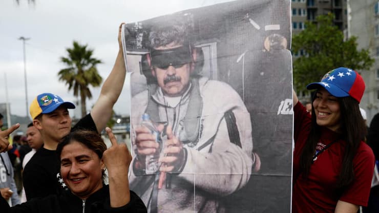 אזרחים מונצואלה חוגגים עם התמונה האיקונית של מדורו האזוק בטרנינג האפור של נייקי (צילום: REUTERS/Juan Gonzalez) אזרחים מונצואלה חוגגים עם התמונה האיקונית של מדורו האזוק בטרנינג האפור של נייקי