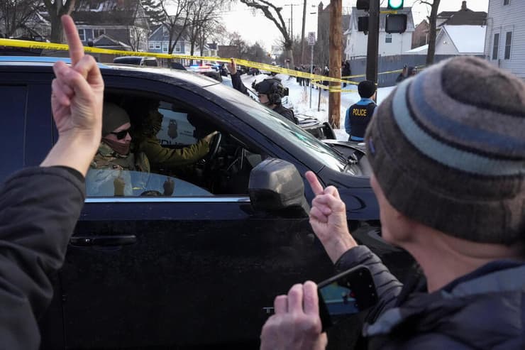 פעילי מחאה מפנים אצבע משולשת לעבר אנשי אכיפת החוק, אתמול ליד זירת ההרג (צילום: REUTERS/Tim Evans) ארה"ב מינסוטה מיניאפוליס מפגינים נגד ICE אחרי הרג ניקול רנה גוד