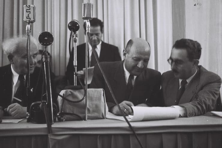 אליעזר קפלן חותם על מגילת העצמאות. מימינו משה שרת ומשמאלו דוד בן גוריון