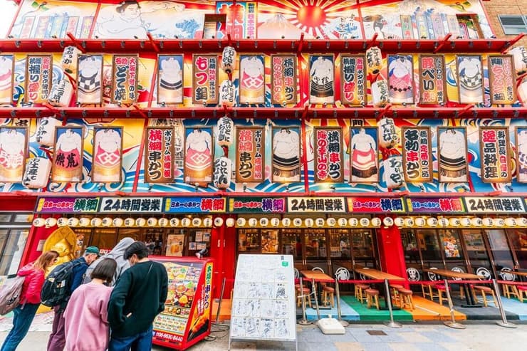 אוסקה, יפן: חזית מסעדת הקושיקאצו הפופולרית יוקוזונה צוטנקאקו, המעוצבת בדיוקנאות מתאבקי סומו, בלב רובע שינסקאי