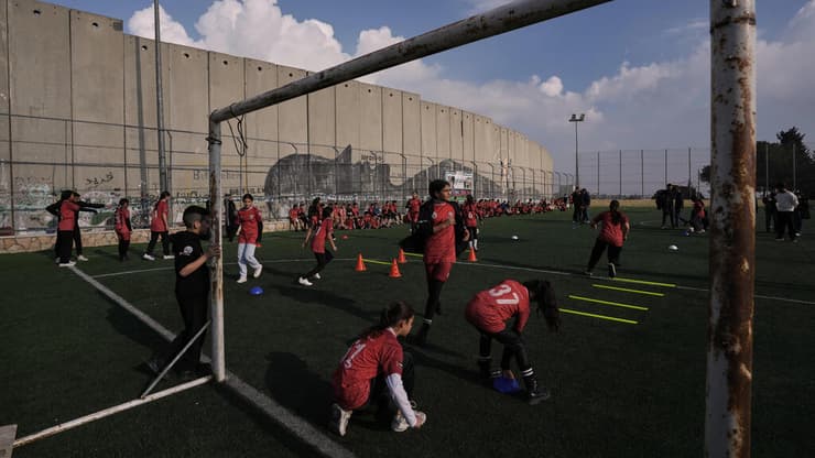 ילדים משחקים על מגרש הכדורגל שנבנה בסמוך לגדר ביטחון