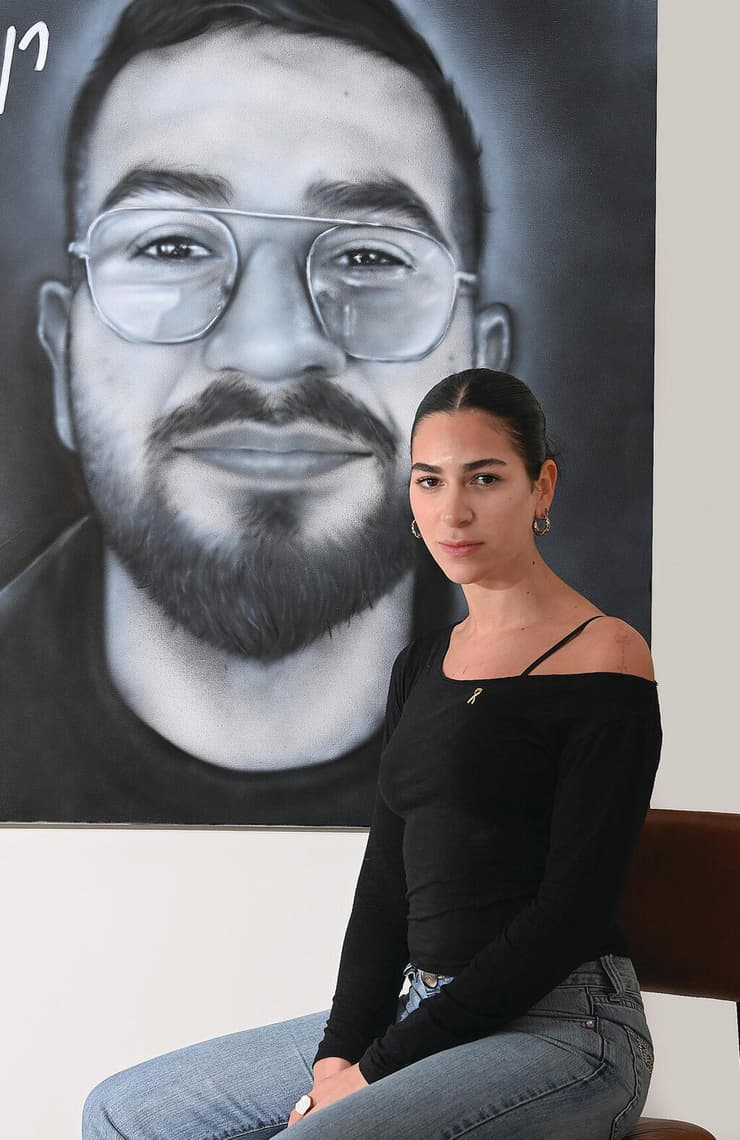 שירה גואילי על רקע דיוקנו של רן, השבוע. "המאבק זה הג'וב 'הנחשק' שלי והוא בחר אותי. אני מקווה שרני גאה בי" | צילום: הרצל יוסף