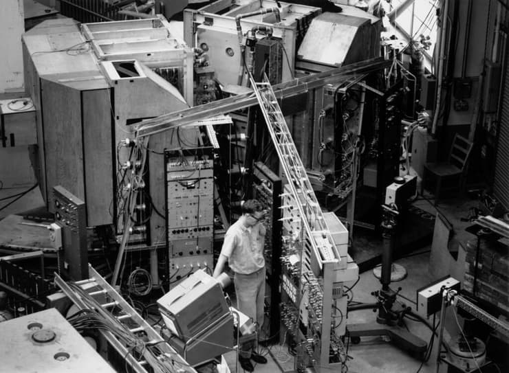 קצת יותר משלושים שנה אחרי גילוי האנטי-חומר התגלו ממצאים שהעידו על קיומם של תהליכים שנותנים לחומר עדיפות על פני האנטי-חומר. המעבדה בברוקהייבן בה נעשה הניסוי 