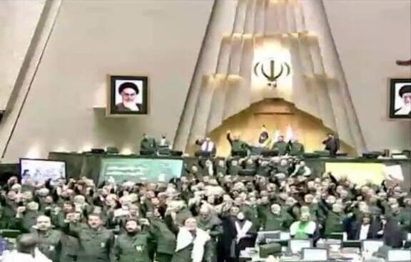 הפרלמנט האיראני, עם תמונת האייתוללה חומייני ברקע חברי פרלמנט באיראן לובשים את מדי משמרות המהפכה לישיבה הבוקר