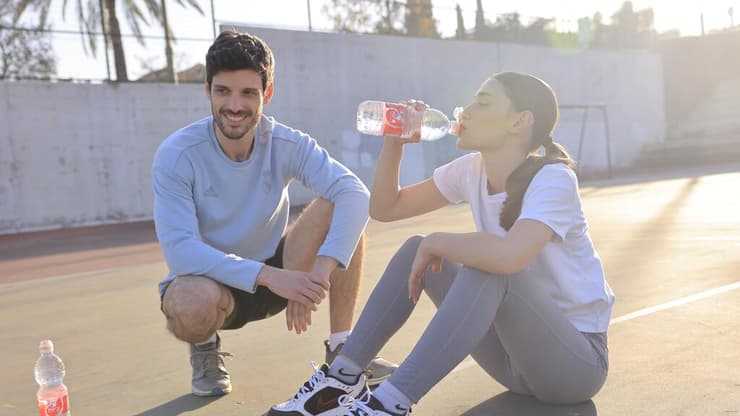 בחורה שותה בקבוק מים נביעות פלוס