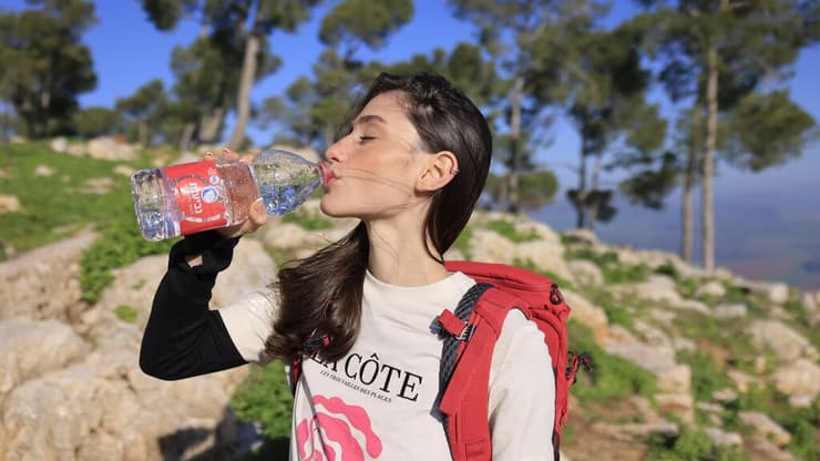 בחורה שותה בקבוק מים נביעות פלוס