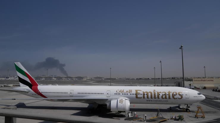 מטוסים של אמירייטס בנמל התעופה בדובאי על רקע תימרות עשן ממתקפה איראנית, אתמול