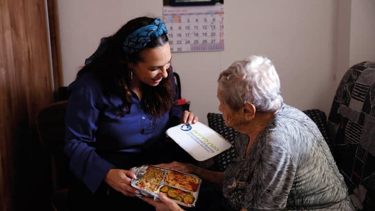 יעל אקשטיין מחלקת מזון לתושבים בבת־ים, שבתיהם נפגעו מירי הטילים האיראני