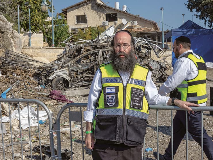 אברהם קאפ, ראש זק"א בית שמש, ומאחוריו שרידי מכוניתה של רונית ז"ל