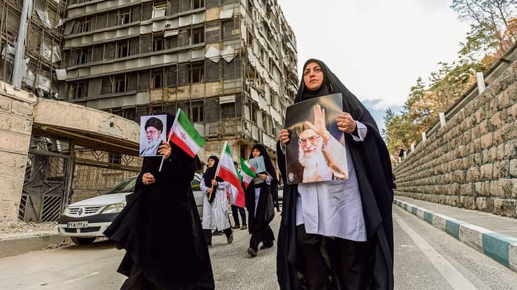 נשים איראניות עם תמונתו של חמינאי ליד בית חולים בטהרן שנהרס בהפצצות | צילום: Majid Saeedi , גטי אימג'ס