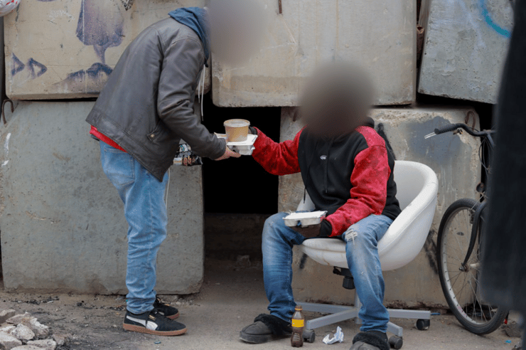 המצוקות שלהם לא הולכות לשום מקום. מתנדב מחלק מזון לדר רחוב בסמטת עכו בתל אביב   