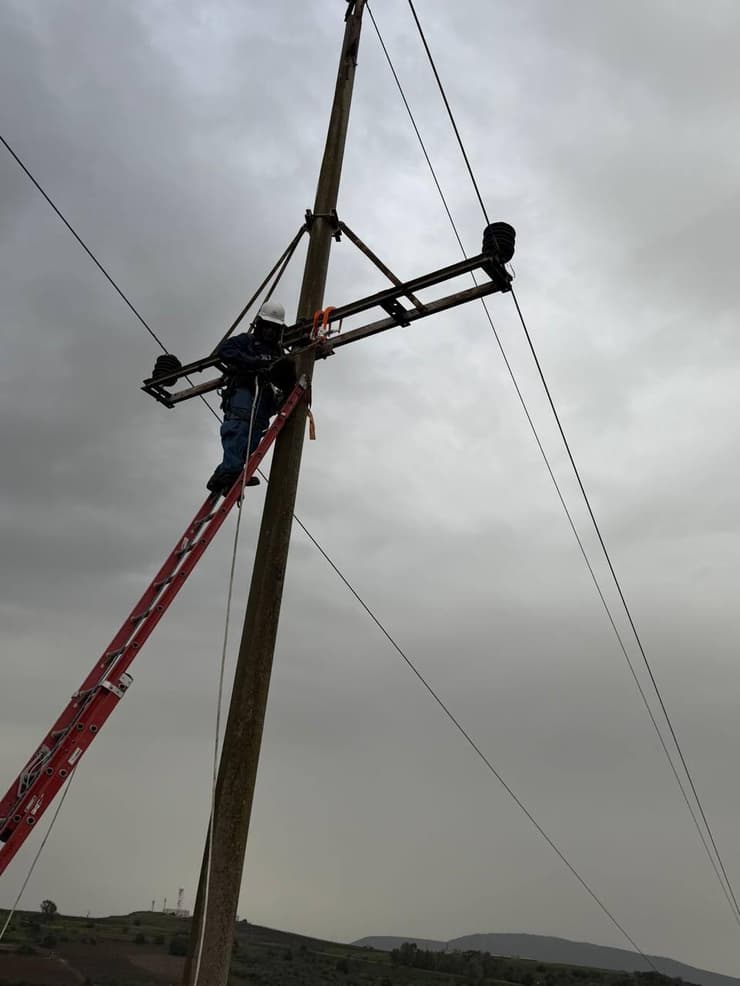אנשי חברת החשמל מתקנים את החוט שנפגע בגליל