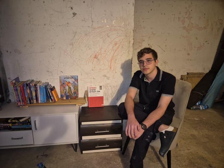 אוליבר ממן במקלט, לצד הספרייה שבנה. "מנסה לנתב את הפחד לעשייה ולעזרה לאחרים" אוליבר ממן במקלט, לצד הספרייה שבנה. "מנסה לנתב את הפחד לעשייה ולעזרה לאחרים"