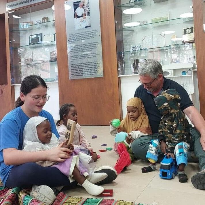 מנכ"ל העמותה סיימון פישר והמתנדבת אלה, עם הילדים המטופלים