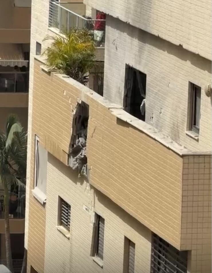 חוקר בקיר הבניין שנפגע בפתח תקווה (צילום: סעיף 27א לפי חוק זכויות יוצרים) בניין בפתח תקווה שנפגע מטיל איראני