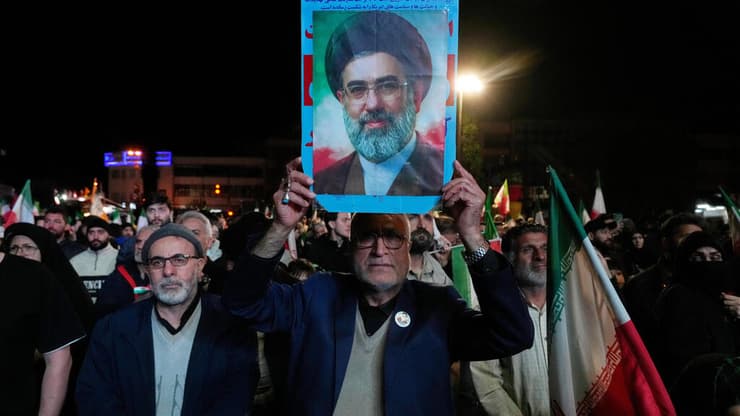 תומכי המשטר האיראני מניפים את תמונתו של מוג'תבא חמינאי לאחר ההודעה על הפסקת האש