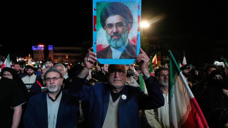 תומכי המשטר האיראני מניפים את תמונתו של מוג'תבא חמינאי לאחר ההודעה על הפסקת האש