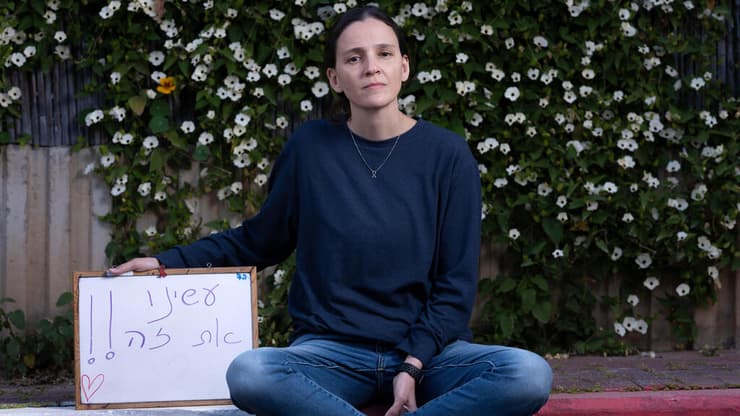 דליה קושניר־הורן עם השלט שכתבו לאחר שובם של יאיר ואיתן הורן