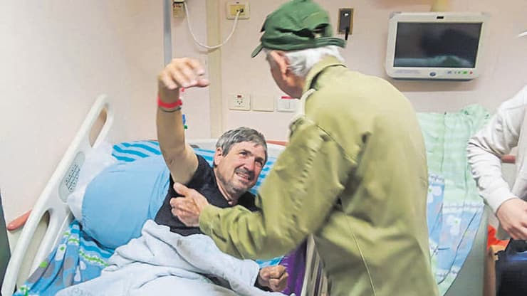 האב עזרא יכין ליד מיטת בנו הפצוע מיכאל יכין
