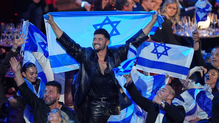 נועם בתן, נציג ישראל לאירוויזיון 2026 בווינה (צילום: AP Photo/Martin Meissner) נועם בתן חוגג עם הדגל