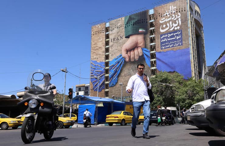 ברחוב בטהרן, עם שלט ענק שבו נראית "יד איראן" אוחזת במצר הורמוז (צילום: ATTA KENARE / AFP) טהרן