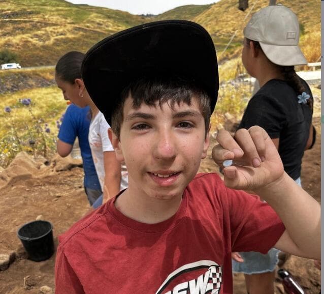 אלון הורוביץ עם אבן החן (צילום: צוות חפירות, כורזים) אלון הורוביץ עם אבן החן