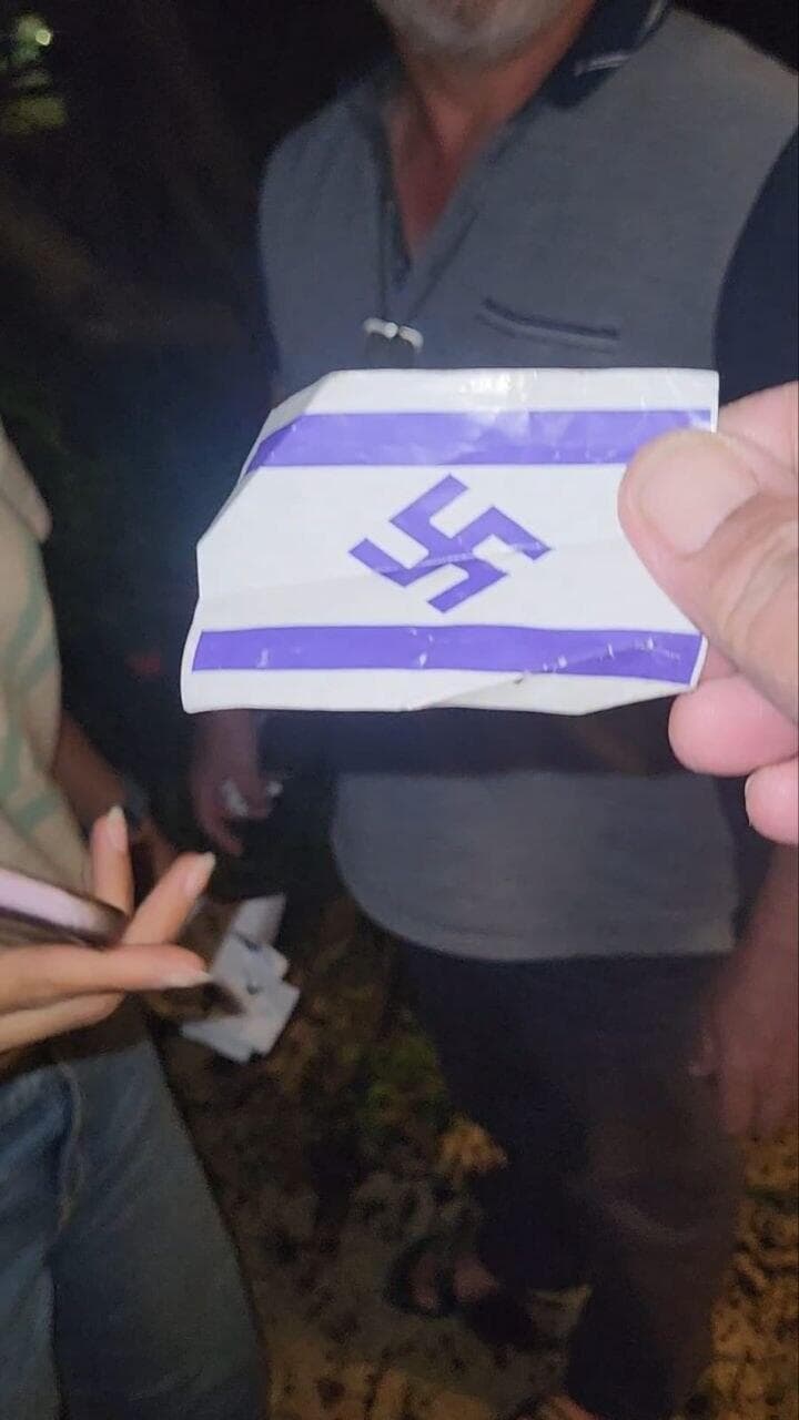 דגל ישראל עם צלב קרס חולק למפגינים מול בית השופט העליון סולברג דגל ישראל עם צלב קרס חולק למפגינים במחאה על חוק הגיוס מחוץ לביתו של שופט העליון סולברג