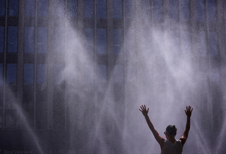 אישה מצטננת במזרקה בעיר קלן (צילום: REUTERS/Thilo Schmuelgen) אירופה גל חום גרמניה קלן צינור מים לקירור