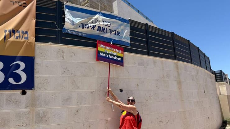 מפגינה מתייחסת על שלט שנתלה נגד המצעד