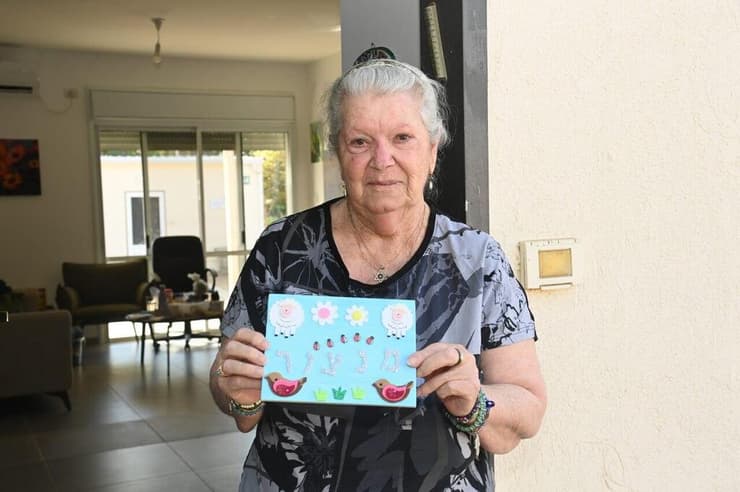 מזל מנצור והשלט לדלת הבית (צילום: הרצל יוסף) מזל מנצור, חוזרת לקיבוץ כיסופים