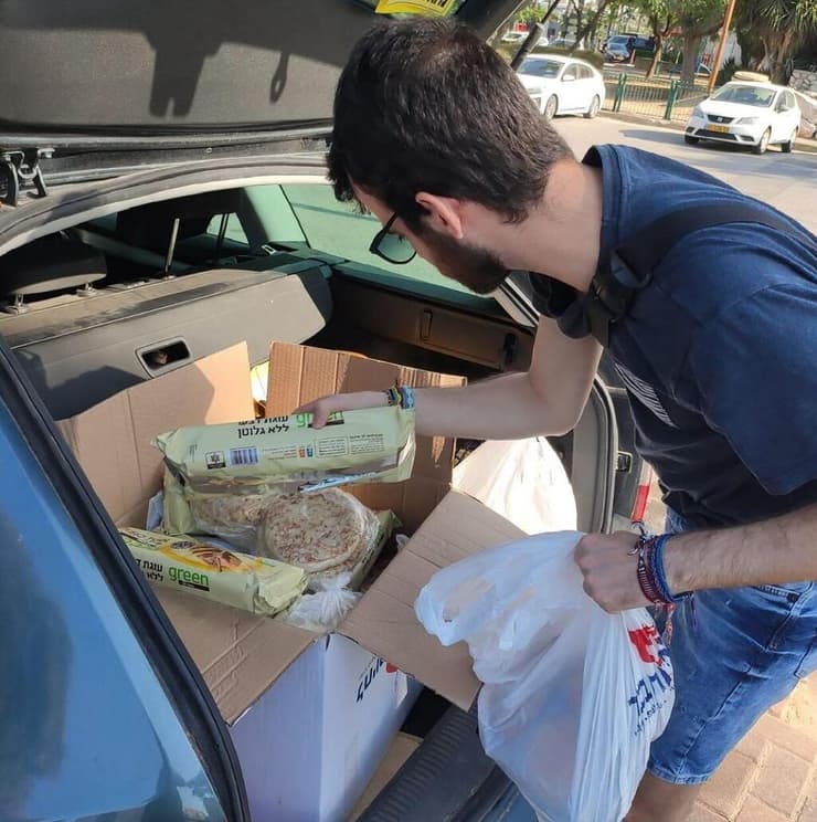 "לראות את הברק בעיניים של ניצולי השואה והקשישים, כשהמתנדב האהוב עליהם מגיע - שווה הכל" (צילום: באדיבות לחיות בכבוד) מתנדב של "לחיות בכבוד" מעמיס מזון למכונית