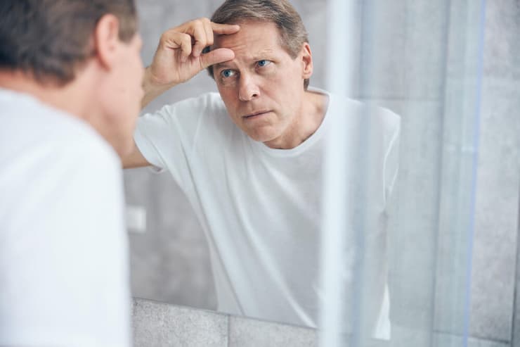 "אם זה מפריע, כדאי לגשת להיבדק" (צילום: shutterstock) גבר בוחן את עצמו במראה