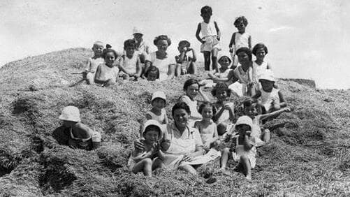 ילדי תל יוסף על ערימת חציר גדולה, 1930 (צילום: יוסף שוייג, ארכיון הצילומים של קק"ל) ילדים על הגורן בתל יוסף