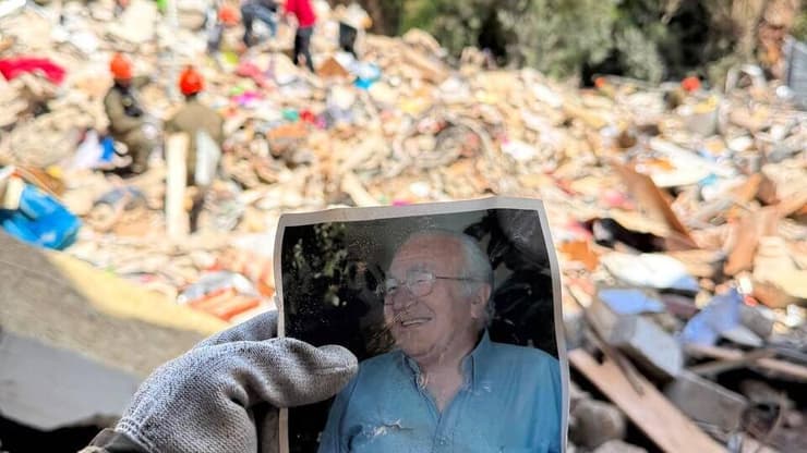 הנכדה יובל מחזיקה את תמונתו של מיכאל באתר ההריסות (צילום: באדיבות המשפחה) האתר הרס הראשון זה הבית של מיכאל כ"ץ ואשתו