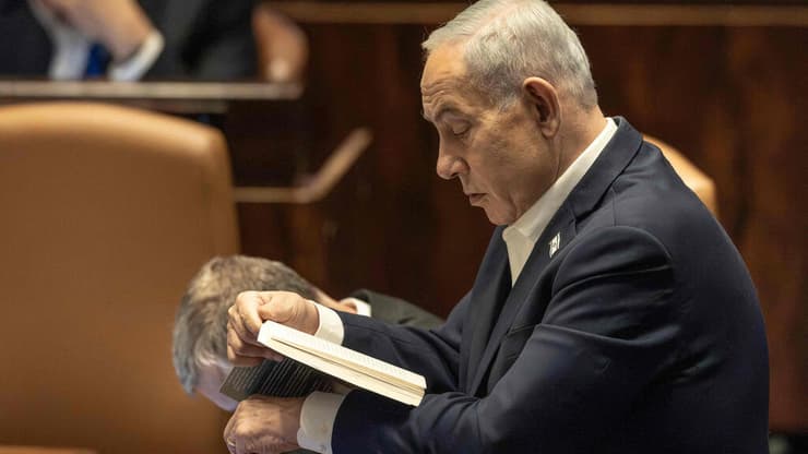 נתניהו קורא ספר בכנסת. בכל הנוגע להצבעה של ישראלים בחו"ל, בינתיים לא נכתב פרק חדש (צילום: ilia YEFIMOVICH / AFP) מליאת הכנסת
