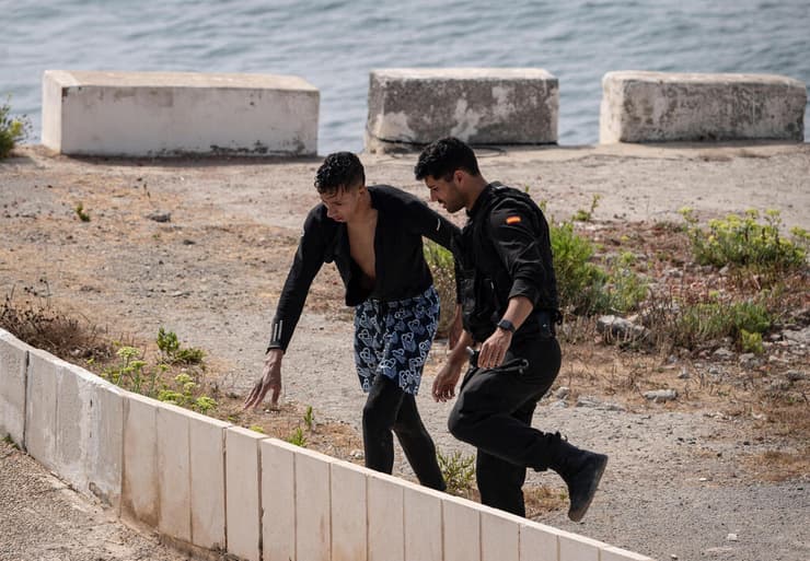 צילום: AP Photo/Antonio Sempere מרוקו ספרד פריצה המונית של מהגרים ל סאוטה איש המשמר האזרחי הספרדי עוזר למהגר שהגיע בשחייה מהים