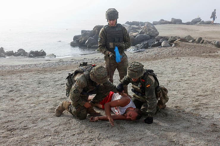 צילום: REUTERS/Jon Nazca חיילים ספרדים מסייעים למהגר שנפצע בניסיון הפלישה לסאוטה